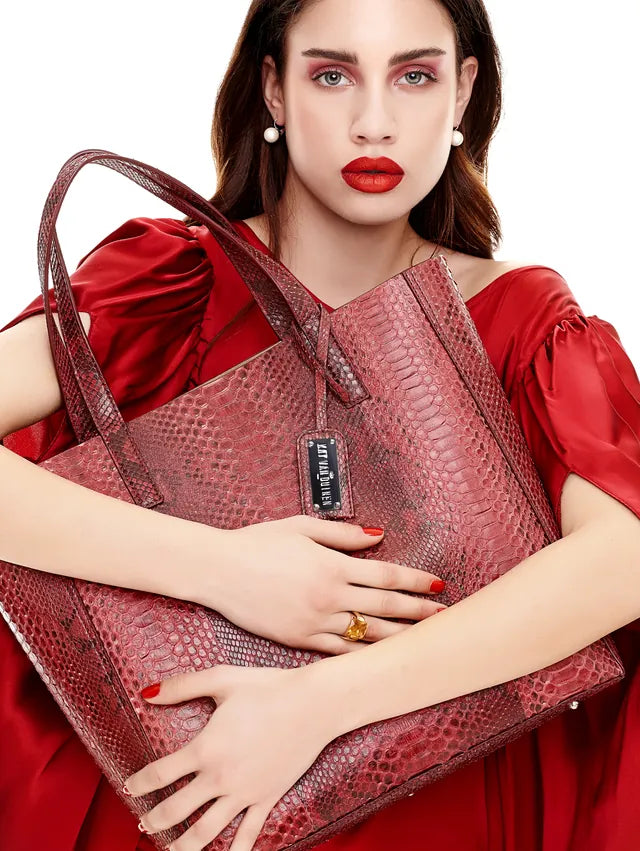 Model in a red dress carrying a large red python-leather tote